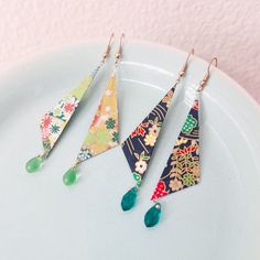 three pairs of earrings are sitting on a plate