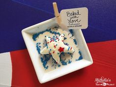 a white plate topped with blue and red sprinkles next to a sign