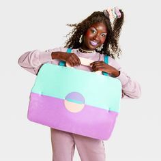 a woman is holding a colorful suitcase and posing for the camera with her hair in pigtails