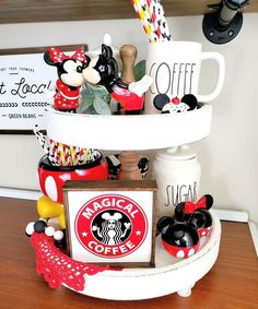 a three tiered tray with coffee cups and mickey mouse figurines