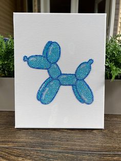 a blue balloon dog sitting on top of a table next to a potted plant