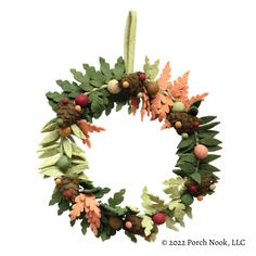 a christmas wreath with pine cones and acorns hanging from a cord on a white background