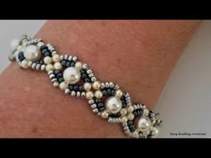 a close up of a person's arm wearing a bracelet with pearls and beads