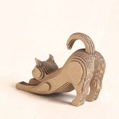 a small wooden cat figurine on a white surface with the tail curled up