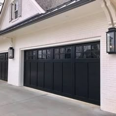 a white house with black garage doors and windows