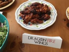 a table topped with plates of food and a sign that says dragon fire wings on it