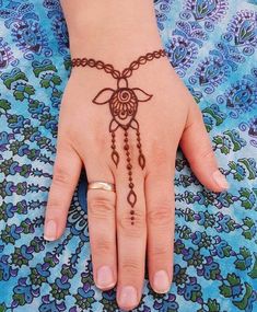 a woman's hand with a henna tattoo on her left hand and a chain attached to the wrist