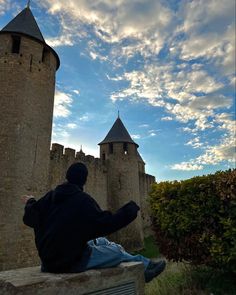 a man sitting on top of a stone bench next to a castle