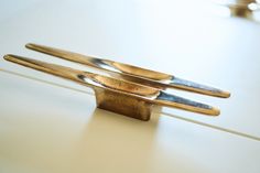 three pieces of metal sitting on top of a white counter next to a faucet