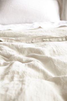 an unmade bed with white sheets and pillows