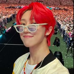 a woman with red hair and sunglasses in front of a large crowd at a concert