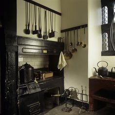 an old fashioned kitchen with pots and pans hanging from the wall