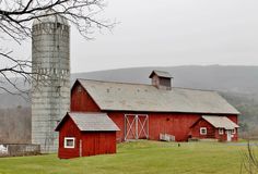 an old red barn with a silo in the background