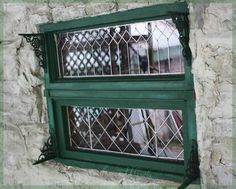 two windows with bars on them in front of a stone wall and window sill