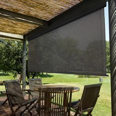 a table and chairs under an awning on a deck with grass in the background