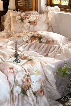 a bed covered in white sheets with pink flowers on it