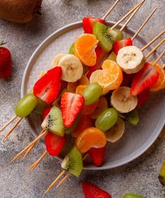 fruit skewers on a plate with strawberries, oranges and kiwi