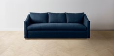 a blue couch sitting on top of a hard wood floor next to a white wall