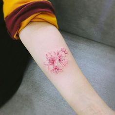 a woman's arm with a pink flower tattoo on the left side of her arm