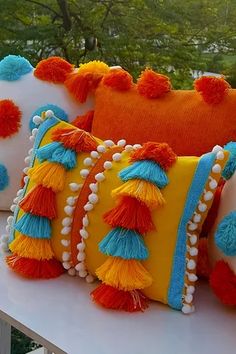 pillows with tassels and pom poms sit on a ledge