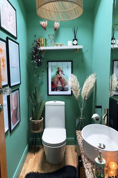 a bathroom with green walls and pictures on the wall