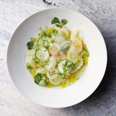 a white bowl filled with cucumbers, onions and cilantro on top of a table