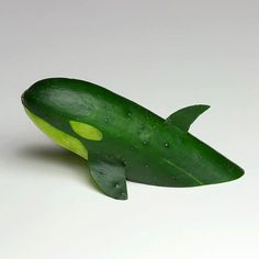 a cucumber shaped like a fish on a white surface