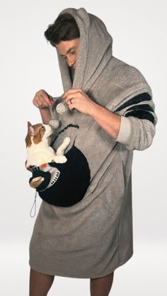 a man in a hoodie is holding a cat