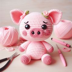 a crocheted pig sitting on top of a table next to yarn and scissors