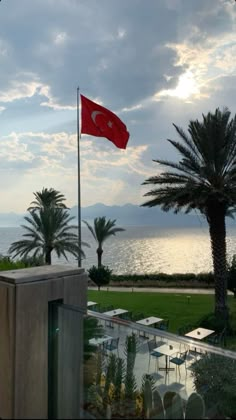 a flag flying in the wind next to a body of water