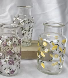 three glass vases sitting on top of a wooden box next to eachother