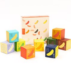 an assortment of colorful wooden blocks sitting in front of a box with fruit on it