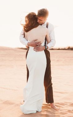 a bride and groom embrace in the desert sand at their elopement photo shoot