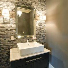 a bathroom with a sink, mirror and lights on the side of the wall in front of it