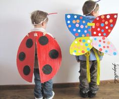 two children wearing paper crafts with ladybug and butterfly wings on their backs, standing next to each other