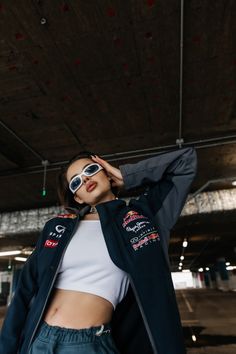 a woman wearing sunglasses and a jacket is posing for the camera with her hands on her head