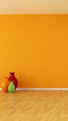 two vases are sitting on the floor in front of an orange wall and wooden floor