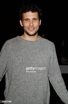 a man smiling and wearing a sweater in the dark