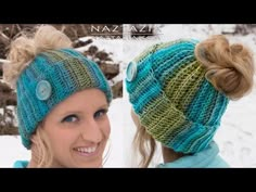 two women wearing knitted hats in the snow, one with a button on it