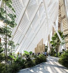 people are walking around inside the building with plants and trees on either side of the walkway