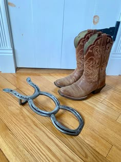 two pairs of cowboy boots sitting on the floor next to a pair of metal scissors