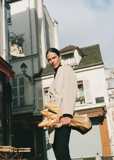 a man standing in front of a building with bread on his feet and holding a bag