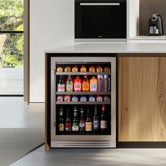 an open refrigerator with drinks in it next to a counter top oven and microwave on the wall