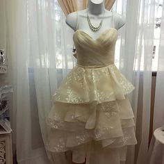 a mannequin dressed in a dress on display next to a window with curtains