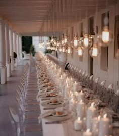 the long table is set with many plates and glasses on it, along with candles