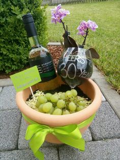 a wine bottle and some grapes in a planter with a bow on the side