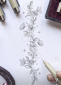 someone is drawing flowers on a piece of paper with some pens and scissors next to it