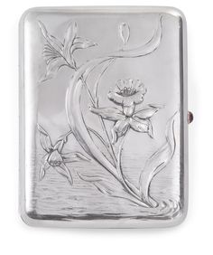 a silver flask with flowers and leaves on the side, in front of a white background