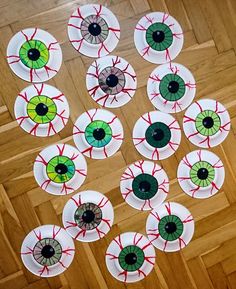 paper plates with eyeballs on them sitting on a wooden floor in the middle of a room