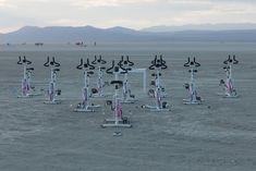 many bicycles are parked in the middle of an empty field with mountains in the background